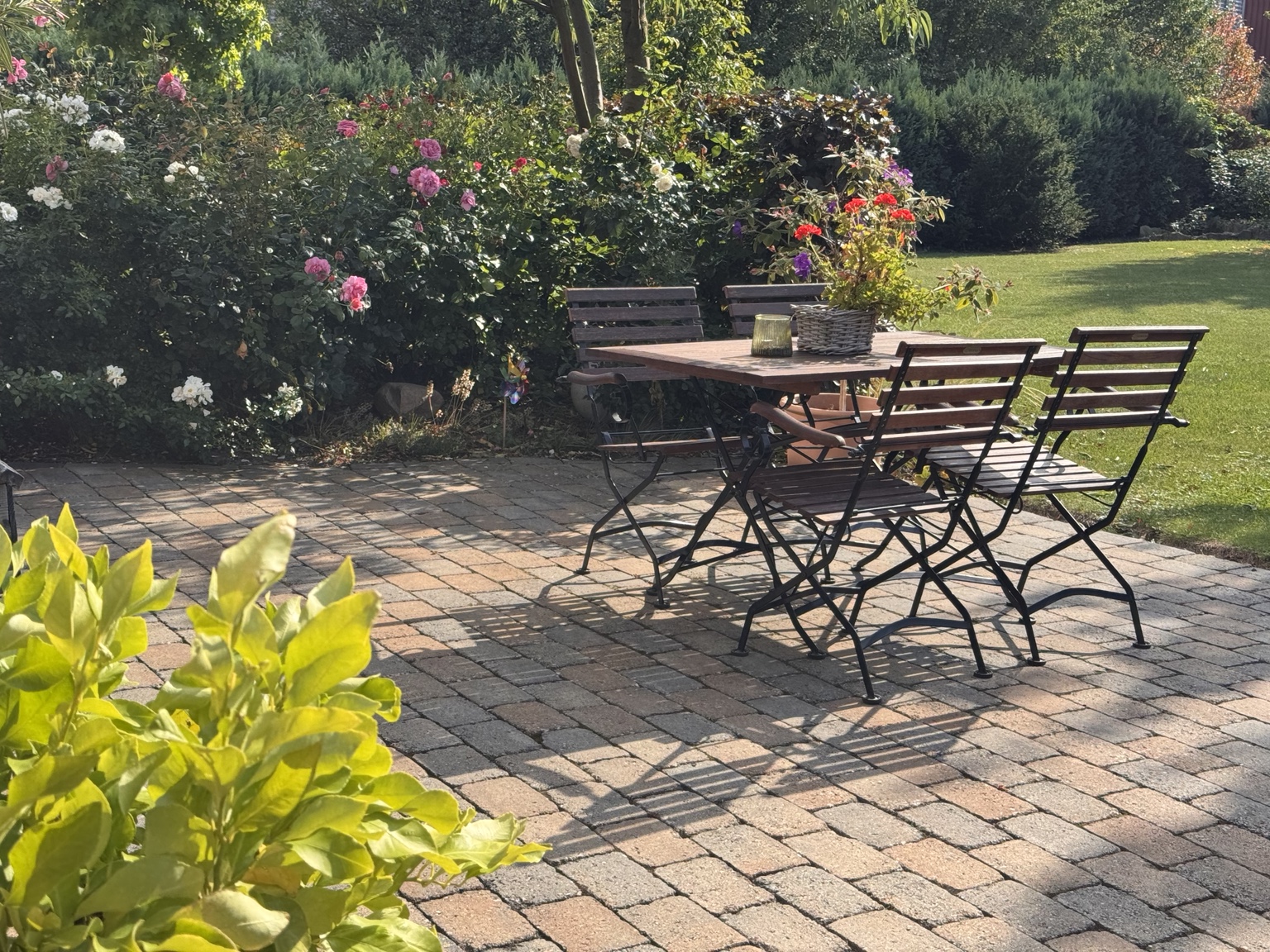Terrasse im Garten mit Tisch, Pflanzen und Bäumen